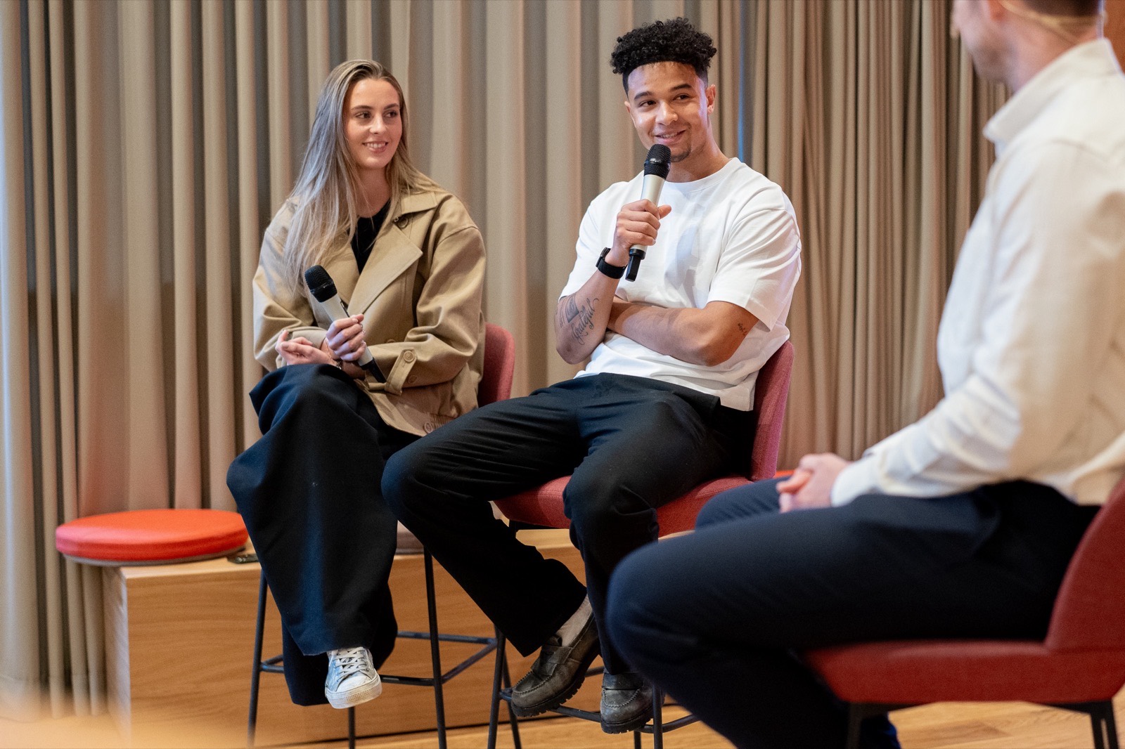 Utøvere og programleder i panelsamtale med mikrofoner